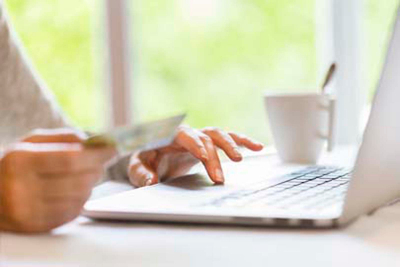 woman using credit card to make purchase on a laptop