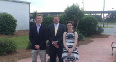 photo of scholarship recipients and bank manager standing outside of school 