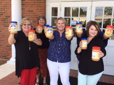 group of ladies enthusiastically holding out jars of peanut butter