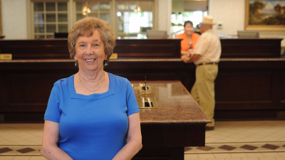 photo of older female standing in bank lobby smiling for camera