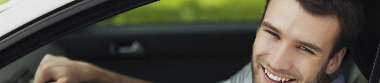 photo of a man looking out of his car window smiling 