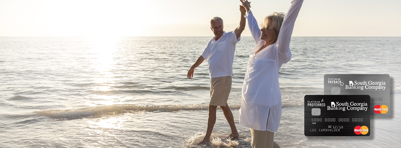 photo of senior couple holding hands and walking through the ocean surf