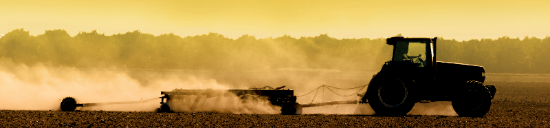 photo of tractor stirring up dust in the field at daybreak